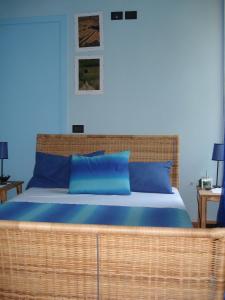 a bedroom with a large wicker bed with blue pillows at Locanda Del Barbaresco in Alba