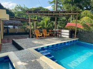 a swimming pool with a table and chairs next to a house at Hotel Manakin Tayrona in El Zaino