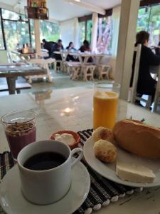 uma mesa com uma chávena de café e um prato de comida em Pousada NAIF em São Lourenço