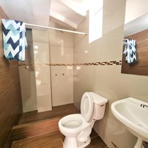 a bathroom with a white toilet and a sink at Apart Hotel El Puma in Cusco