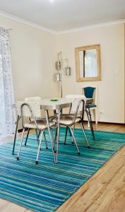 a dining room with a table and chairs on a rug at Decades in Port Willunga