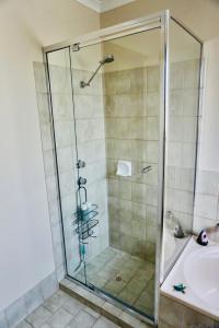 a shower with a glass door next to a sink and a tub at Decades in Port Willunga