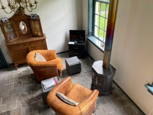 a living room with two chairs and a wood stove at Logies Oud Bergveen in Veenhuizen