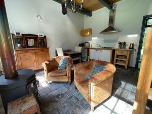 a living room with two chairs and a kitchen at Logies Oud Bergveen in Veenhuizen