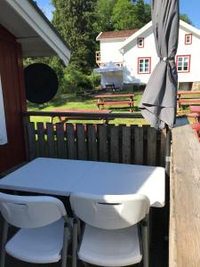 - une table et des chaises sur une terrasse couverte avec un parasol dans l'établissement Björsjöås Vildmark - Small camping cabin close to nature, à Olofstorp