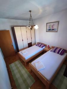 Cette chambre comprend deux lits et un lustre. dans l'établissement Apartment Dragi - 250 m from beach, à Supetar