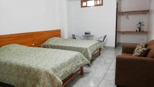Cette chambre comprend deux lits, une chaise et un canapé. dans l'établissement Excelente ubicación! Bellas y cómodas habitaciones en el centro de Oxapampa, à Oxapampa