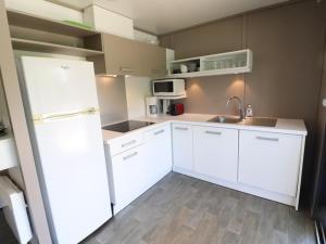 uma cozinha com armários brancos e um frigorífico branco em Gîte Le Rouget-Pers, 3 pièces, 4 personnes - FR-1-742-362 em Le Rouget