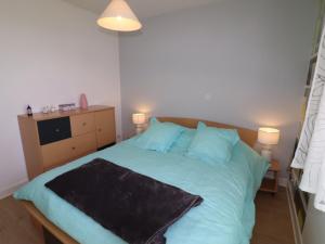 - une chambre avec un lit avec des draps bleus et deux lampes dans l'établissement Appartement Aurillac, 2 pièces, 2 personnes - FR-1-742-389, à Aurillac
