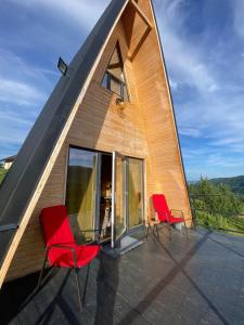 two red chairs sitting on the roof of a house at Cabana A-Frame Refugiu Montan in Băişoara