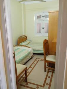 ein kleines Schlafzimmer mit einem Bett und einem Stuhl in der Unterkunft شارع ٨٩ فيلا ٢٤ in ‘Izbat al Burj