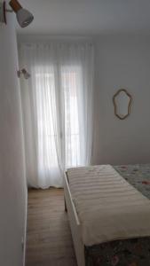 sypialnia z łóżkiem i oknem z białymi zasłonami w obiekcie Appartement Perpignan w Perpignanie