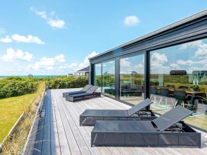 une maison avec une terrasse offrant une vue sur l'océan dans l'établissement 6 person holiday home in L kken, à Løkken
