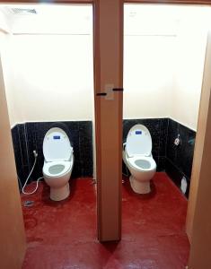 two toilets in a bathroom with the door open at Footprints Hostel in Coron