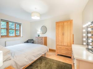 a bedroom with a bed and a dresser and a mirror at Ringland Cottage in Attlebridge