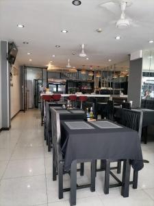 a dining room with black tables and chairs in a restaurant at Amici Miei Guest House in Patong Beach