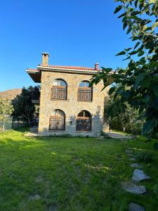 a large brick house with windows on a grass field at KİNZİ İMROZ in Gokceada Town