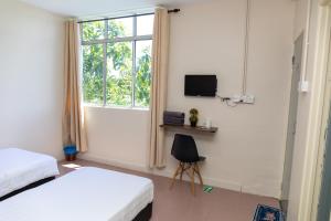 a bedroom with two beds and a window and a chair at Familia Motel Kangar in Kangar