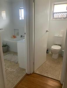 a white bathroom with a toilet and a sink at Room in a Family home in Gold Coast
