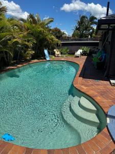 a swimming pool with a brick walkway around it at Room in a Family home in Gold Coast