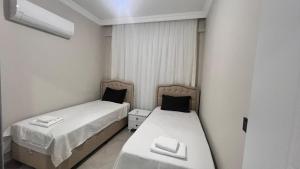 2 Betten in einem kleinen Zimmer mit weißen Wänden in der Unterkunft SELİNTİ CİTY DAİRE 1 Suit in Gazipasa