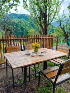a wooden picnic table with two chairs and flowers on it at Guest House Temi In Gudani 