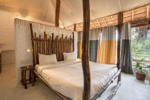 a bedroom with a four poster bed and a window at Deshadan Eco Valley Resort - An Eco friendly Mud House in Kanthalloor