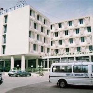 een wit busje geparkeerd voor een groot gebouw bij Hotel Shalimar Rawalpindi in Rawalpindi