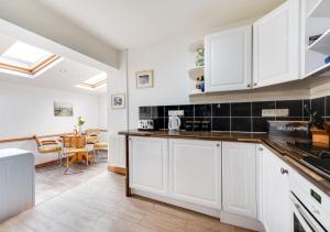 a kitchen with white cabinets and a dining room at Sea View in Saundersfoot