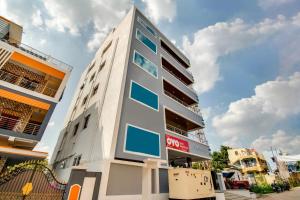 a tall white building with blue windows at Rvn Guest Inn in Nellore