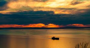 a boat on the water with a sunset in the background at Dream Views at Arthurs Seat B & B in Arthurs Seat