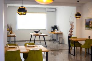 a dining room with tables and green chairs and a screen at Boutique rooms Kican in Metković