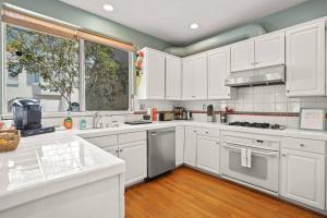 cocina con armarios blancos y ventana grande en Beautiful Spacious House 2BR / 4BR in Silver Terrace en San Francisco