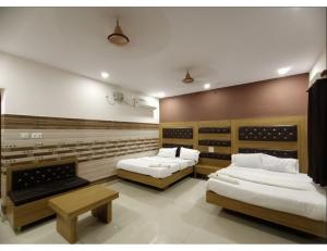 a room with two beds and a bench in it at Chhabra Guest House, Kanpur in Kānpur