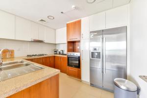 uma cozinha com um frigorífico de aço inoxidável e armários de madeira em Burj Vista, Downtown Dubai Collection em Dubai