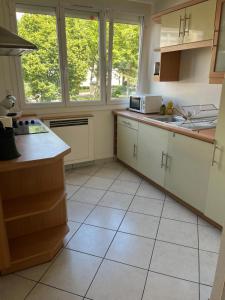 a kitchen with white cabinets and tile floors and windows at Zénith de Rouen - Sud 3 - Diochon - Parc Expo in Le Grand-Quevilly +5 photos