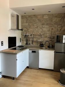 a kitchen with white cabinets and a stone wall at Charmant appartement cosy in Saint-Raphaël