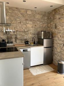 a kitchen with white appliances and a stone wall at Charmant appartement cosy in Saint-Raphaël