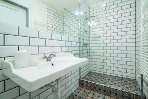 a white bathroom with a sink and a mirror at Fifteen Boutique Rooms Budapest with Self Check-In in Budapest