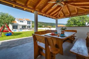 a patio with a wooden table and chairs and a playground at NEW Villa Anja is a 4 bedroom villa with a 32 sqm heated pool near Imotski in Imotski
