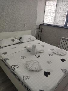 uma cama com um cobertor branco com padrões a preto e branco em Студия №2-65 LifeHouseAlmaty в ЖК Теремки-2 em Almaty
