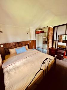 a bedroom with a large bed and a mirror at Avocado Cottages in Khadkagaon