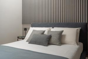 Una cama con almohadas blancas y grises. en Santa Croce Design Apartment R&R, en Venecia