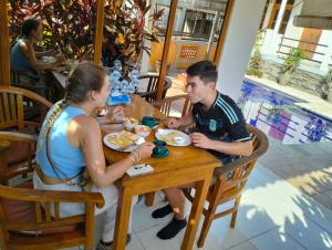 羅威那的住宿－Kaia Lovina Guest House，坐在餐桌旁吃食物的男人和女人