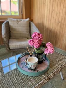 - une table basse avec un vase de fleurs et une tasse dans l'établissement Neringarent Apartamentai, à Juodkrantė