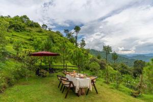 a table with chairs and an umbrella on a field at StayVista at Leopard's Creek with Pool in Solan