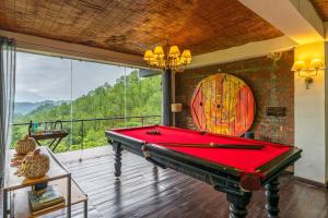 a pool table in a room with a large window at StayVista at Leopard's Creek with Pool in Solan