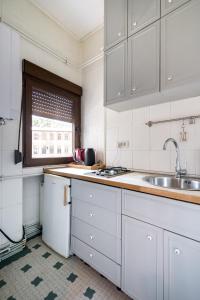 een keuken met witte kasten, een gootsteen en een raam bij Sleek Comfort - A Blend of Style and Convenience in Boekarest