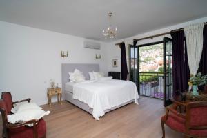 a bedroom with a white bed and a balcony at Nomad Rooms in Mostar