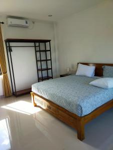 1 dormitorio con 1 cama con marco de madera en Limun guesthouse, en Ujung